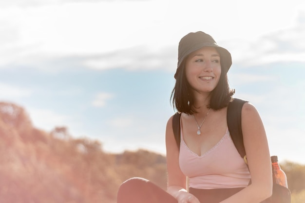 Portret van een gelukkige blanke toeristenvrouw die op de top van de berg zit te rusten