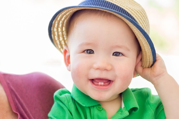 Portret van een gelukkige gemengde ras Chinese en blanke jongen die zijn hoed draagt