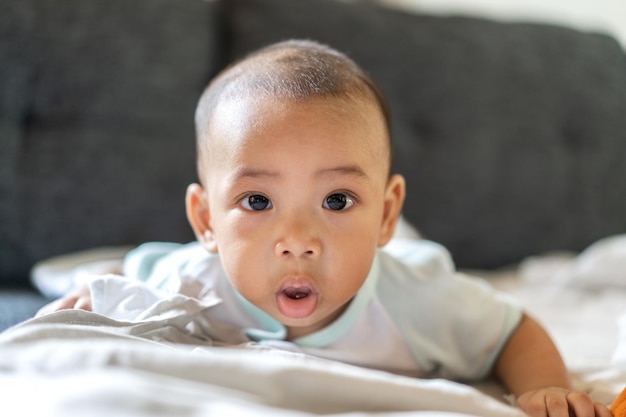 Portret van een gelukkige glimlach aziatische babyjongen die ontspant terwijl hij naar de camera kijkt schattig aziatisch pasgeboren kind op het bed thuis