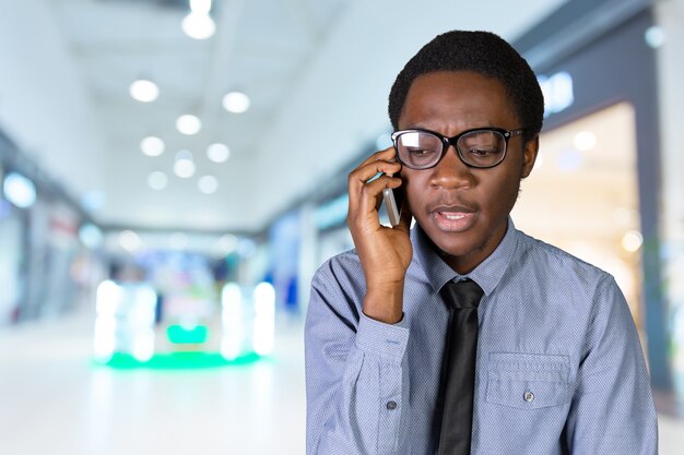 Portret van een gelukkige jonge Afrikaanse man met een mobiele telefoon