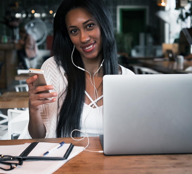 Portret van een gelukkige jonge afrikaanse vrouw in een coffeeshop met mob