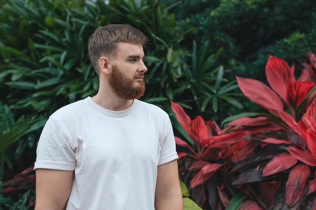 Portret van een gelukkige jonge bebaarde man met baard die diep inademt en frisse lucht inademt op natuurlijke achtergrond