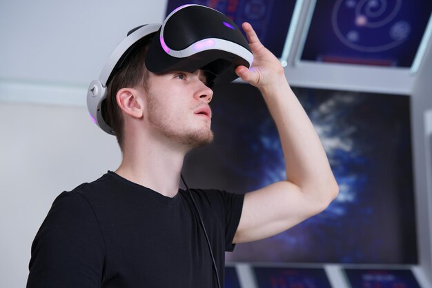 Portret van een gelukkige jonge knappe man die een modern apparaat gebruikt met een virtual reality-headsetmasker of een 3d ar vr-bril die het spel speelt mensen en technologie metavers concept