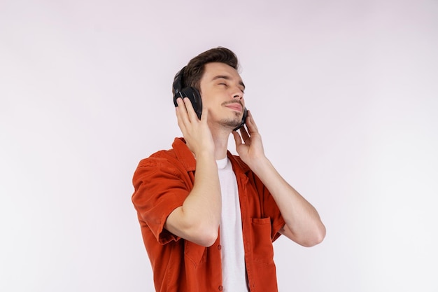 Portret van een gelukkige jonge man die een koptelefoon draagt en geniet van muziek op een witte achtergrond