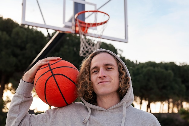 Portret van een gelukkige jonge man met een basketbal op een stadshofconcept van stedelijke sport in de straatkopieerruimte voor tekst