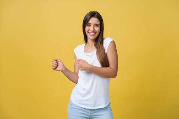 Portret van een gelukkige jonge vrouw die danst op gele achtergrond