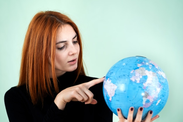 Portret van een gelukkige jonge vrouw die de geografische bol van de wereld in haar handen houdt