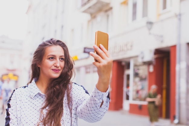 Portret van een gelukkige jonge vrouw die een selfie maakt tijdens het wandelen in de stad