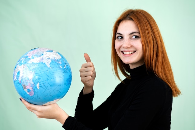 Portret van een gelukkige jonge vrouw die geografische wereld van de wereld in haar handen.