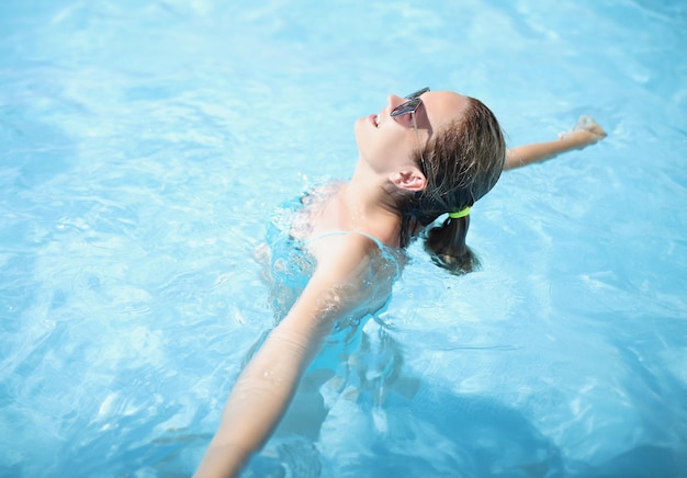 Portret van een gelukkige jonge vrouw die in het zwembad zwemt, geniet van de zon, zonnebaadt in het water, ontspannen sfeer op vakantie, zonnige dag. Vakantie, resort, hotel, leuk concept