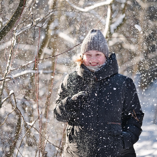 Foto portret van een gelukkige jonge vrouw die op een winterdag door het bos loopt.