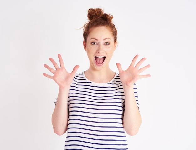 Foto portret van een gelukkige jonge vrouw die tegen een witte achtergrond gebaren maakt