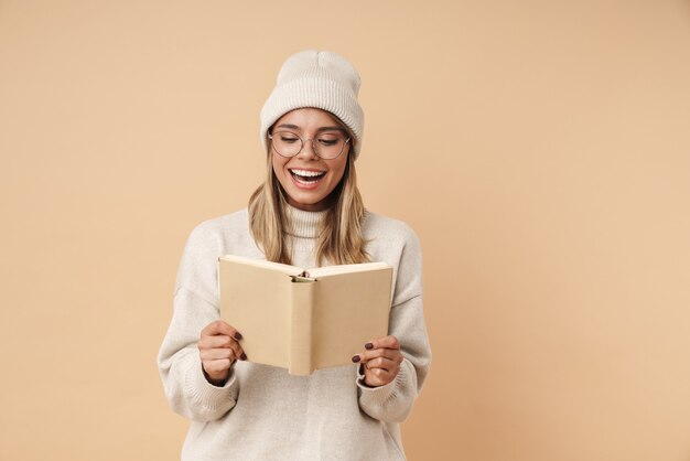 Portret van een gelukkige jonge vrouw in een bril die lacht en een boek leest