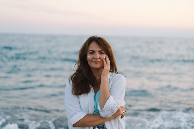 Portret van een gelukkige jonge vrouw op een achtergrond van prachtige zee het meisje kijkt naar de magische zee vrijheid en geluk