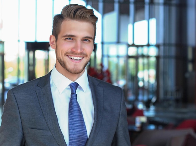 Portret van een gelukkige jonge zakenman die in de lobby van het hotel staat