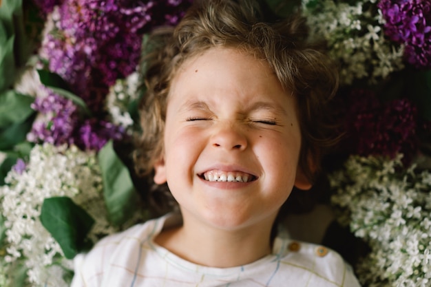 Portret van een gelukkige jongen in lila bloemen. Gelukkige jeugd. lentetijd