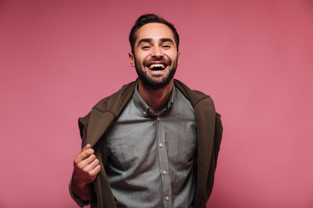 Portret van een gelukkige kerel die zijn jas uittrekt en lacht