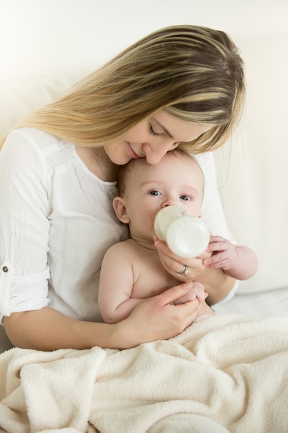 Portret van een gelukkige moeder en haar baby die uit de fles eet