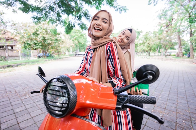 Portret van een gelukkige moslimvriend die samen buiten op een motorfiets scooter rijdt