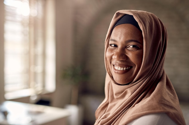 Portret van een gelukkige moslimzakenvrouw die naar de camera in haar kantoor kijkt