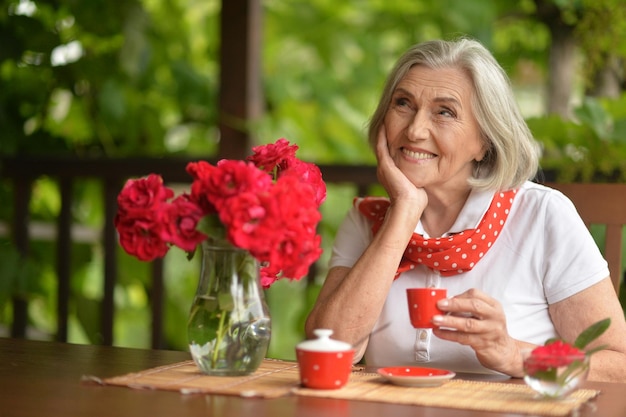 Portret van een gelukkige oude vrouw die koffie drinkt