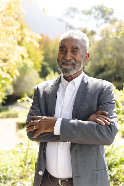 Portret van een gelukkige oudere man van twee rassen die thuis in de zonnige tuin glimlacht