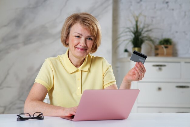 Portret van een gelukkige oudere senior dame positieve vrouw met een creditcard die online in de winkel betaalt