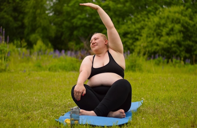 Portret van een gelukkige plus size vrouw die buiten yoga beoefent