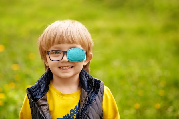 Portret van een gelukkige scheelziende jongen 4-5 jaar oud. Lente park.