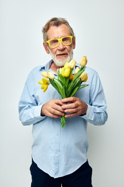 Portret van een gelukkige senior man een boeket bloemen met een bril als een geschenk lichte achtergrond