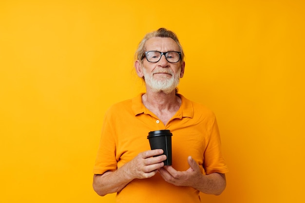 Portret van een gelukkige senior man in een gele t-shirt een glas met een drankje bijgesneden weergave