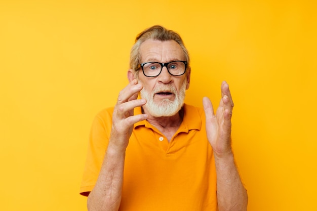 Portret van een gelukkige senior man met een gele bril met een geel shirt die ongewijzigd poseert