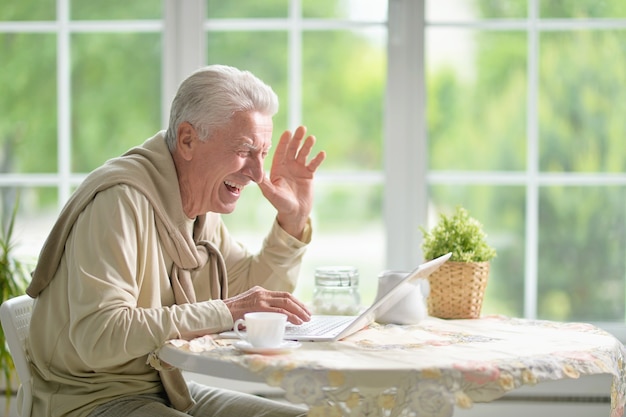 Portret van een gelukkige senior man met laptop