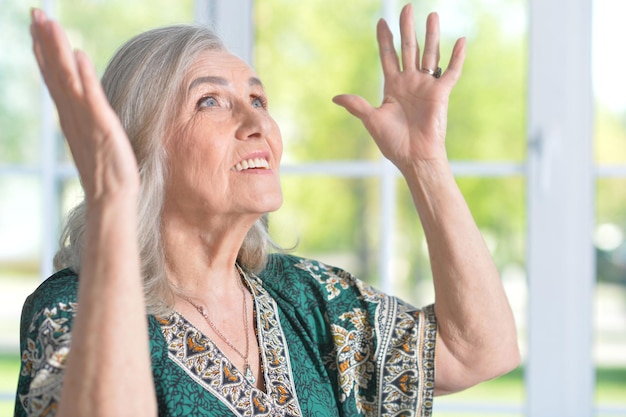 Portret van een gelukkige senior vrouw in een groen shirt die thuis poseert