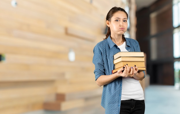 Foto portret van een gelukkige studentenmeisje of -vrouw met boeken in bibliotheek