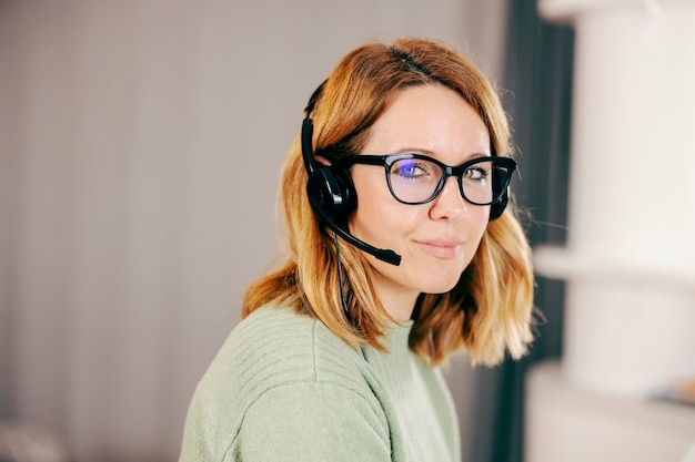 Portret van een gelukkige telewerker met headset die online vanuit huis werkt