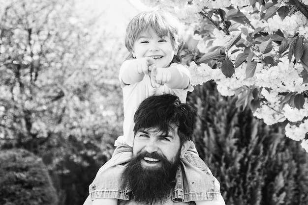 Portret van een gelukkige vader die zoon meelift op zijn schouders en vader opkijkt met zoon h