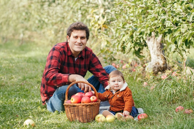 Portret van een gelukkige vader en zoon die zitten terwijl fruit in een mand in het park zit