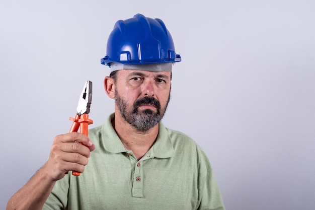 Foto portret van een gelukkige, volwassen architect in een helm die een mannelijke industriële inspecteur uit de jaren 60 draagt met een shirt dat in de studio poseert