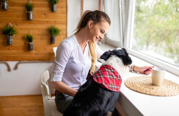 Foto portret van een gelukkige vrouw die thuis met haar hond speelt