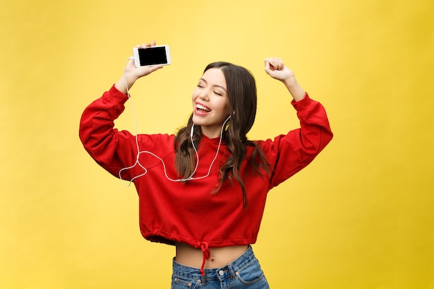 Portret van een gelukkige vrouw luisteren muziek in oortelefoons en dansen