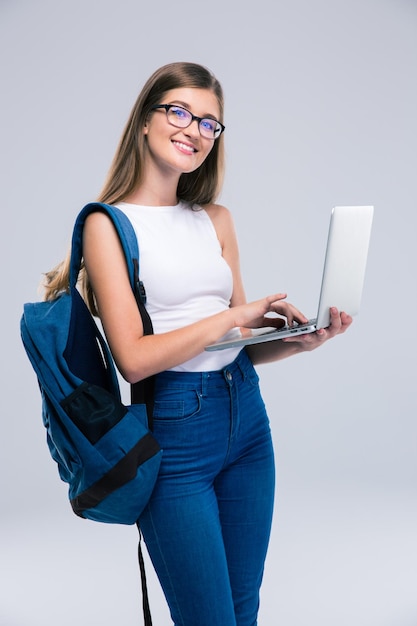 Portret van een gelukkige vrouwelijke tiener die geïsoleerde laptop met behulp van