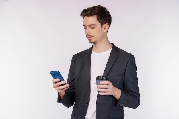 Portret van een gelukkige zakenman die smartphone gebruikt en warme koffie over wit houdt