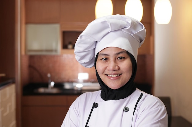 Portret van een gelukkige, zelfverzekerde, succesvolle Aziatische vrouwelijke chef-kok die naar de camera kijkt en glimlacht