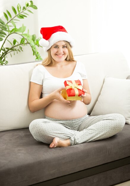 Portret van een gelukkige zwangere vrouw die in de doos van de kerstcadeau kijkt