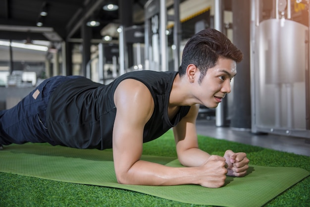 Portret van een geschiktheidsmens die planking oefening in gymnastiek doen