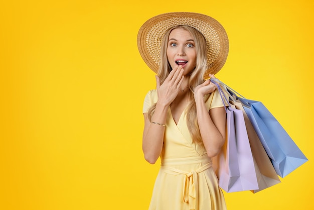 Portret van een geschokt meisje in een jurk die boodschappentassen vasthoudt en naar de camera kijkt