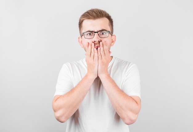 Portret van een geschokte jonge man die zijn mond behandelt met handen