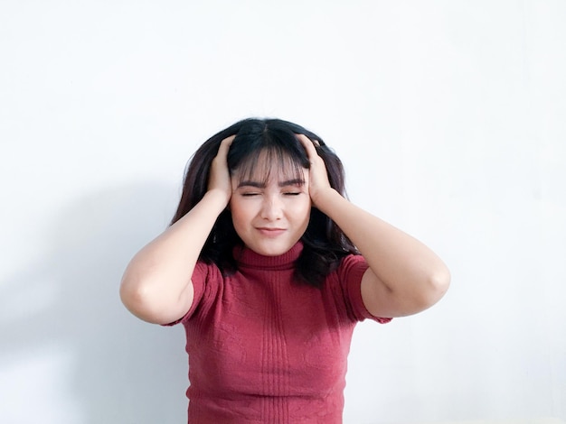 Portret van een gestresste jonge vrouw die het hoofd in handen houdt met de achtergrond Ongelukkig Aziatisch meisje met een bezorgde, gestresste gezichtsuitdrukking die naar beneden kijkt