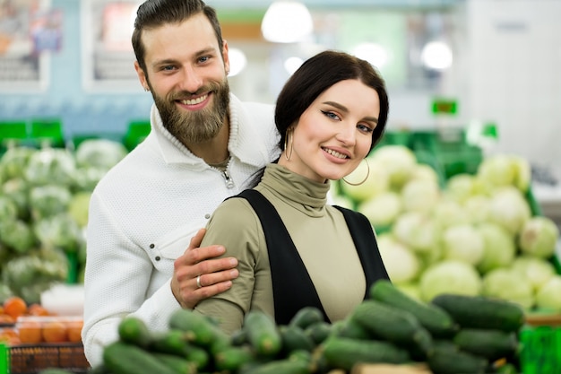 Portret van een gezond paar kijken naar groenten en fruit in de supermarkt tijdens het winkelen